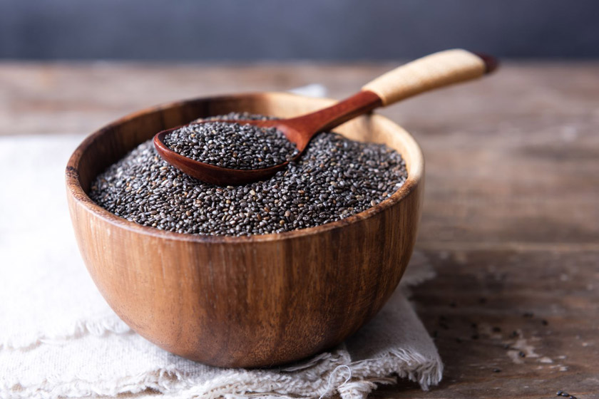 A bowl of chia seeds with a wooden spoonAI-generated content may be incorrect.